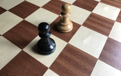 Black and white pawns on wooden chessboard