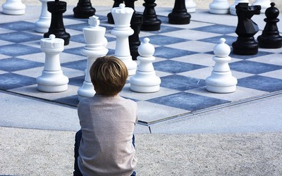 a boy sitting in front of a giant chessboard