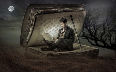Man sitting with a laptop under the cover of a giant book