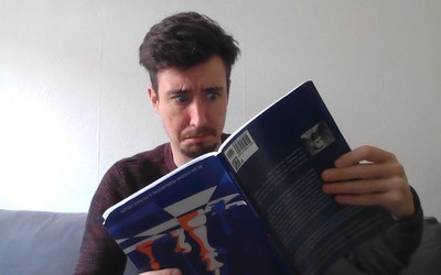 Me holding a chess book upside down with a confused expression